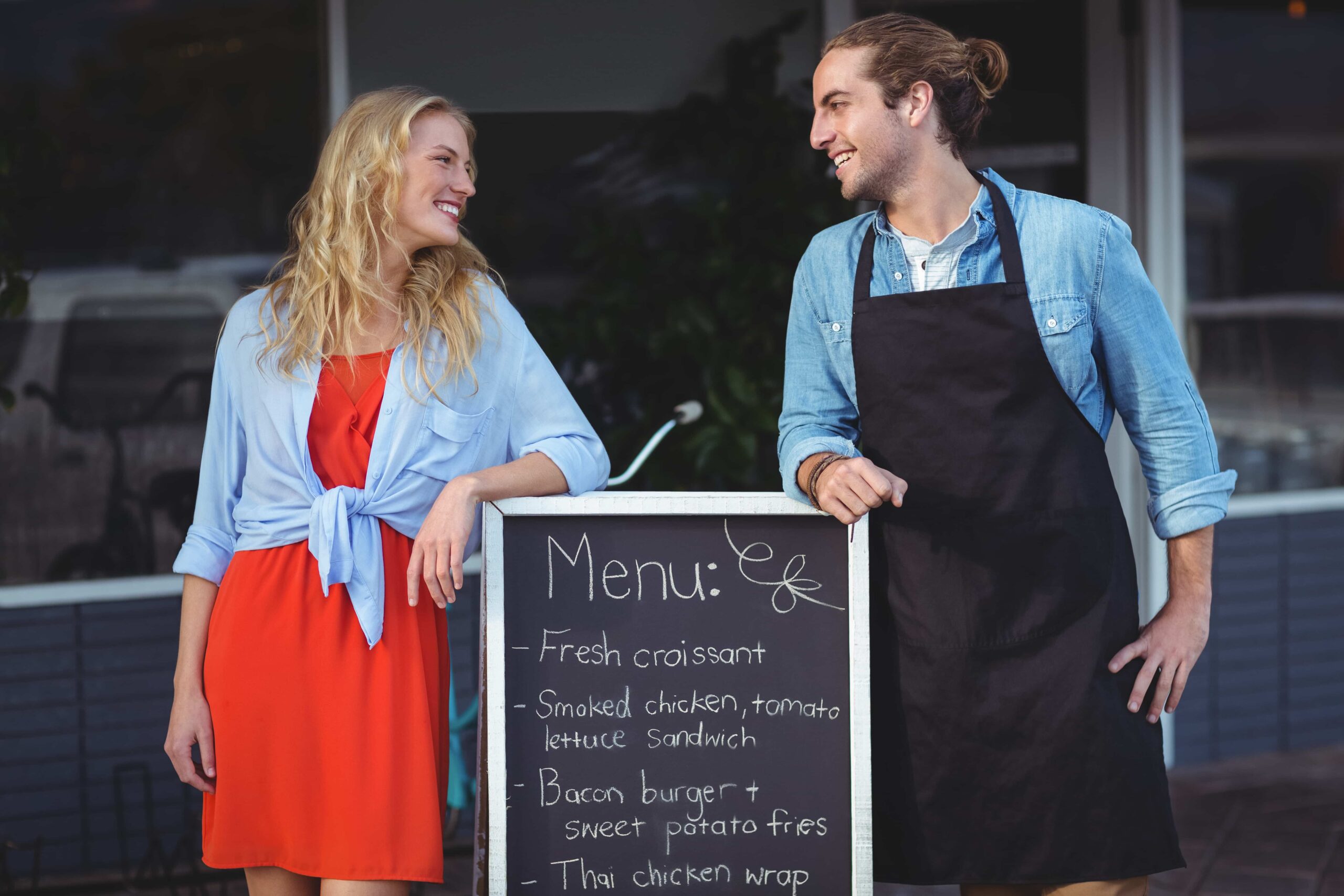 waiter-woman-standing-with-menu-board-outside-cafe (1) Restaurant Advertising Services